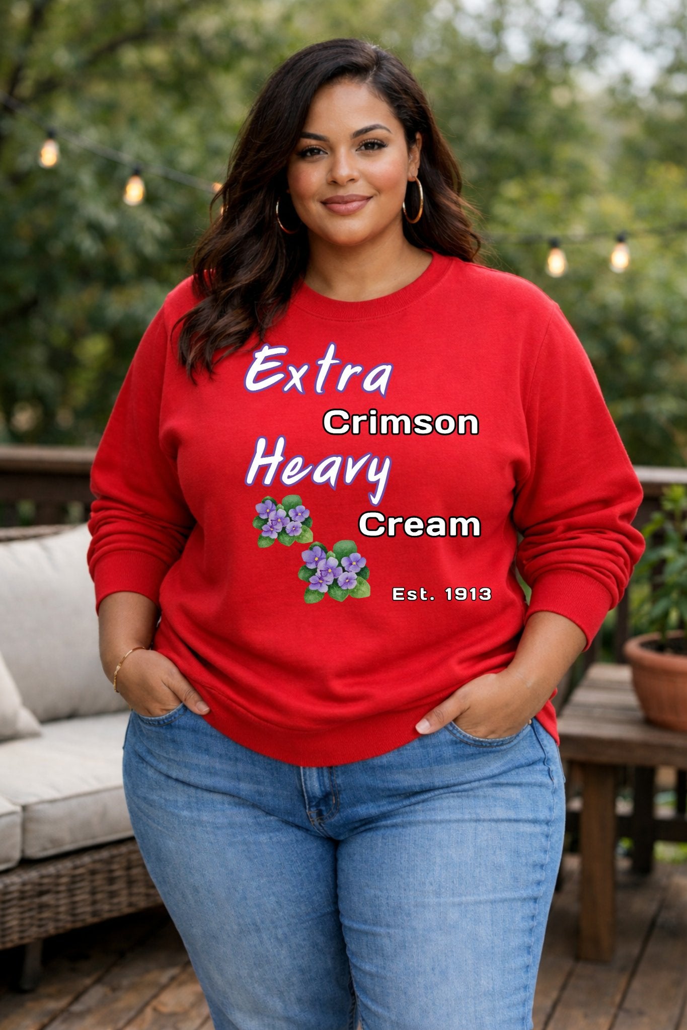Woman wearing a red sweatshirt with text and flower graphics outdoors.